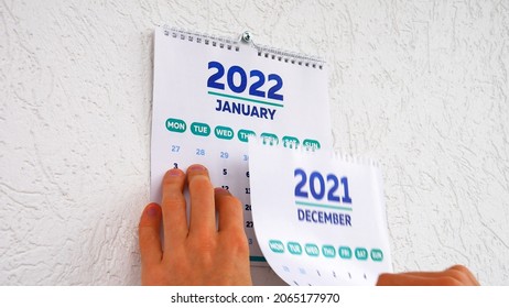 A Man's Hands Tear Off The December Page Of A 2021 Calendar On The Wall Followed By The January Page Of A New 2022 Calendar