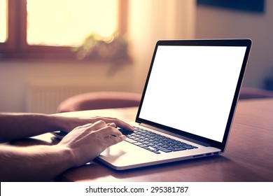 Man's hands using laptop with blank screen on desk in home interior. - Shutterstock ID 295381787