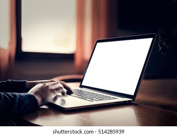 Man's Hands Using Laptop With Blank Screen On Desk In Home Dark Interior.