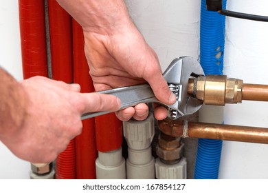 Man's hands with wrench turning off valves