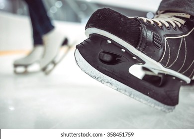 Man's hockey skates and women's figure skates on ice background