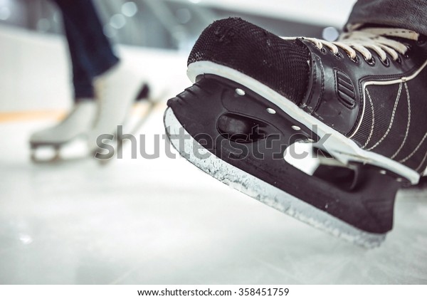 Man\'s hockey skates and women\'s figure skates\
on ice background