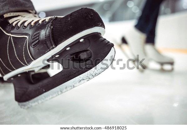 Man\'s hockey and women\' figure skates on ice\
background. Selective focus on\
edges.