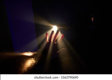 Man's Palm Is Trying To Stop Rays Of The Bright Light At Dark Room.