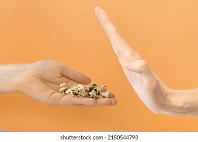 Man's refusing burnt dark popcorn on an orange background. Deny. Destroy. Roasted. Corn. Disallow. Ember. Dirty. Charred. Ignore. Unhealthy. Lost - Shutterstock ID 2150544793