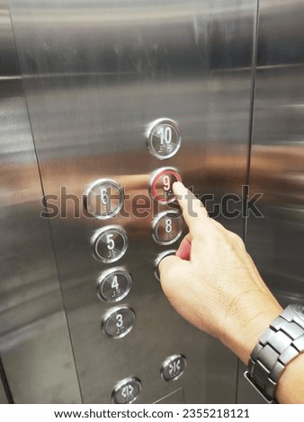 A man's right hand is pressing the elevator button to the 9th floor.