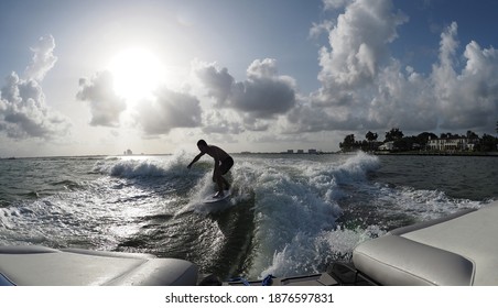 Man's Silhouette Wake Surfing Behind Boat With Sun On The Background