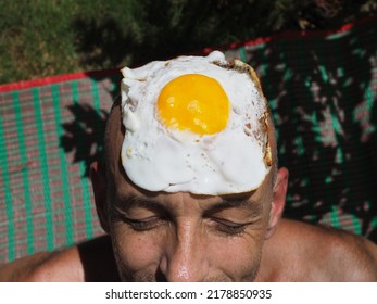 Mans Sweaty Face  On Picnic Matt With Fried Egg On Head Blurred Background 