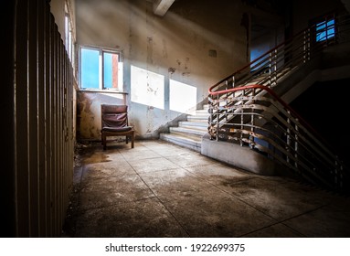 Mansfield, Nottingham - 3rd June 2017 Old general hospital building abandoned one single empty chair with eerie creepy sun light rays shining in on dark old haunted decaying staircase landing
