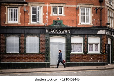 Mansfield, Nottingham UK January 2021 - Lone Woman Walking Past Closed Down Boarded Up Pub Public House As Town Goes Into Recession And Shops Close Under Covid 19 Pandemic Lockdown