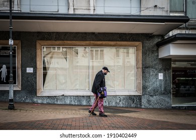 Mansfield, Nottingham UK January 2021 - Lone Old Man Wearing Mask Walking Past Closed Down Boarded Up Retail Super Store As Town Goes Into Recession And Shops Close Under Covid 19 Pandemic Lockdown