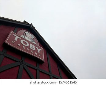 MANSFIELD, UK - NOVEMBER 24, ‎2019: Purple And White Sign And Exterior Of Toby Carvery Watermill,  The Traditional Home Of The Roast Dinner, Against A Grey, Cloudy Autumn Sky At Sutton-in-Ashfield