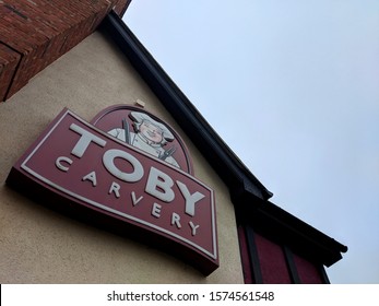 MANSFIELD, UK - NOVEMBER 24, ‎2019: Purple And White Sign And Exterior Of Toby Carvery Watermill,  The Traditional Home Of The Roast Dinner, Against A Grey, Cloudy Autumn Sky At Sutton-in-Ashfield