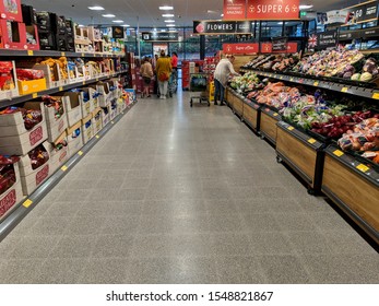 MANSFIELD, UK - NOVEMBER 3, 2019:  Fresh Fruit, Vegetable & Crisps Aisle In A Newly Open Aldi Supermarket. Customers Shopping & Queuing At Checkouts To Pay For Their Groceries In The Background