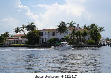 Mansion on the Intracoastal Waterway in Boca Raton, Florida with Small Boat Passing, Back-Lit by Sun with Cloudy Sky Overhead, Late Summer Afternoon
