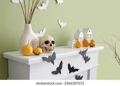 Mantelpiece with Halloween decor and paper bats on green wall in room - Powered by Shutterstock