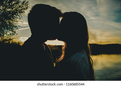 Manti, UT / United States - May 15, 2014: Silhouette Of Young Couple Kissing At Sunset On The Lake  