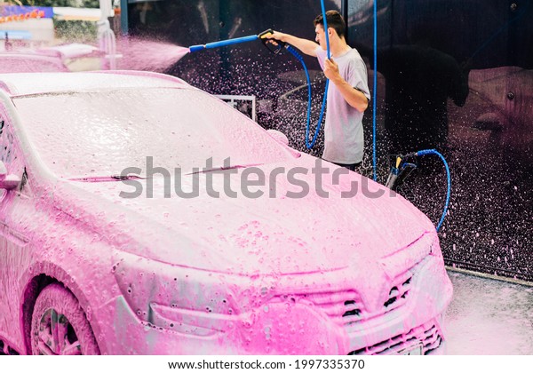 Manual car wash with pressure water on the street,\
Summer car wash, Car wash with high pressure water, Car wash with\
pink foam
