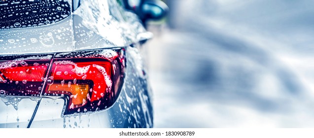 Manual car wash with white soap, foam on the body. Washing Car Using High Pressure Water. - Shutterstock ID 1830908789
