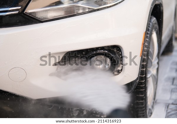 Manual car wash with white soap, foam on the body.\
Close up. Manual car wash outside. High Pressure Water. Cleaning\
Car Using Washing with\
soap.