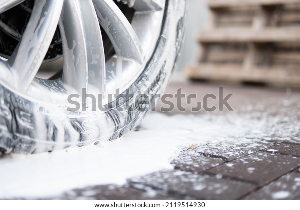 Manual car wash with white soap, foam on the\
body. Washing with soap. Cleaning Car Using High Pressure Water.\
Manual car wash outside. Close\
up.