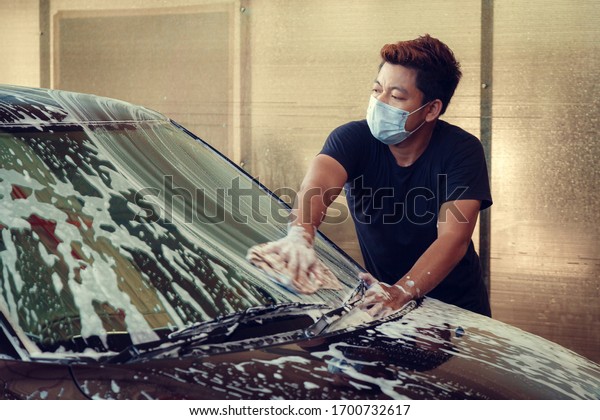 Manual car\
washing cleaning with foam and pressured water at service station.\
Man worker washing car in a car\
wash
