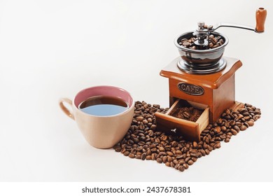 Manual coffee grinder, cup of strong coffee, heart-shaped coffee beans on a white isolated background. Copy space. Coffee is my favorite drink.
