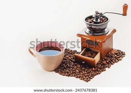 Manual coffee grinder, cup of strong coffee, heart-shaped coffee beans on a white isolated background. Copy space. Coffee is my favorite drink.