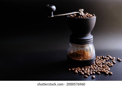 Manual coffee grinder on black background with roasted and heaps of coffee beans. Make coffee to freshen up in the morning, drifting coffee