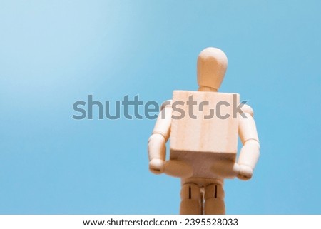 Manual handling at work. Wooden manikin holding a box. Handling technique. Health and safety at work.