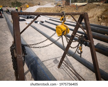 Manual Hoist And PVC Pipes In Protective Metal Covers. Industrial Pipeline Mantling At Construction Site