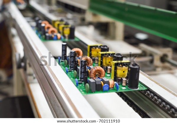 Manual insertion of\
electronic components on printing circuit board assembly before\
wave soldering. The image taken in a electronic production plat on\
a conveyor belt.  