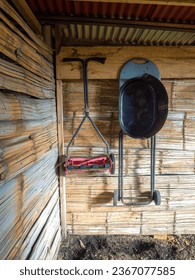 A manual lawn mower and a  basic black grill hanging from a cane wall in a rustic shed, in a farm near the colonial town of Villa de Leyva in central Colombia.