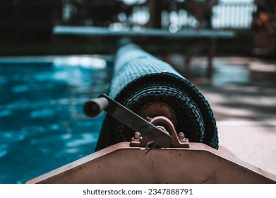 Manual real for a retractable floating pool cover to keep out leaves and keep in heat.