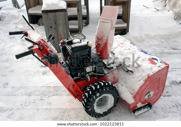 A manual snow plow or snow cleaning\
machine in the alps switzerland in a hotel\
garden