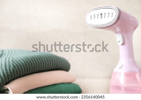 Manual steamer with sweaters on a blurry background. Ironing clothes with hot steam
