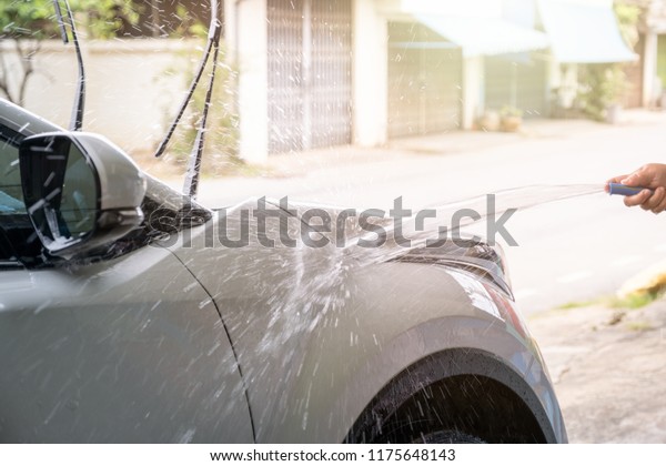 Manual\
washing car with pressure water hose on white\
car