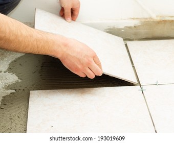 Manual worker covering bathroom floor with caremic tiles. - Shutterstock ID 193019609