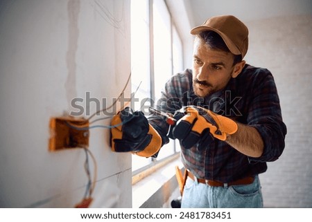 Manual worker installing electric cables at construction site. Copy space.
