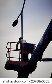 Manual worker on a telescopic lifter basket fixing street light pole.