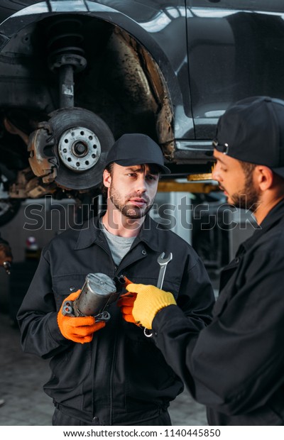 manual workers repairing car with tools in\
mechanic workshop