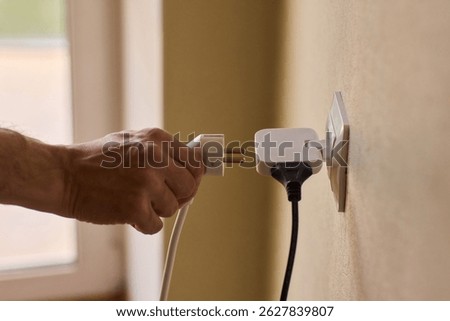Manually plugging an electrical device into a wall outlet for convenient use and power