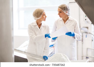 Manufacture, Industry, Food Production And People Concept - Women Technologists With Paper And Powdered Milk At Ice Cream Factory Shop