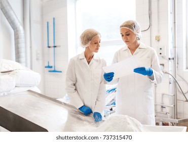 Manufacture, Industry, Food Production And People Concept - Women Technologists With Paper And Powdered Milk At Ice Cream Factory Shop