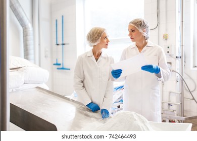 Manufacture, Industry, Food Production And People Concept - Women Technologists With Paper And Powdered Milk At Ice Cream Factory Shop