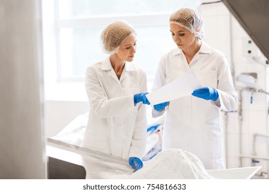 Manufacture, Industry, Food Production And People Concept - Women Technologists With Paper And Powdered Milk At Ice Cream Factory Shop