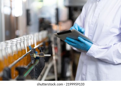 Manufacturer checking product bottles fruit juice on the conveyor belt in the beverage factory. Worker checks product bottles in beverage factory. Inspection quality control