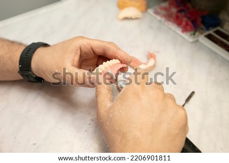Manufacturing of dentures. Orthopedist's hands make jaw prostheses.
