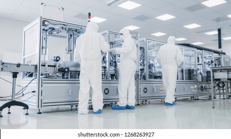In the Manufacturing Facility Team of Scientist Wearing Sterile Protective Coverall Set's up  Programs Modern Industrial 3D Printer, High Precision Manufacture of Semiconductors under Process.