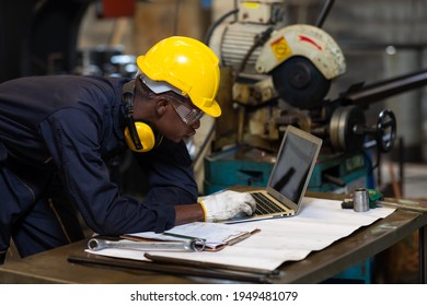 Manufacturing Factory black male Mechanical Engineer Works on Personal Computer at Metal lathe industrial manufacturing factory. Engineer Operating lathe Machinery. American African people.